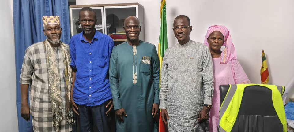Équipe dirigeante de la Coopérative NDAM au bureau, devant le drapeau du Sénégal